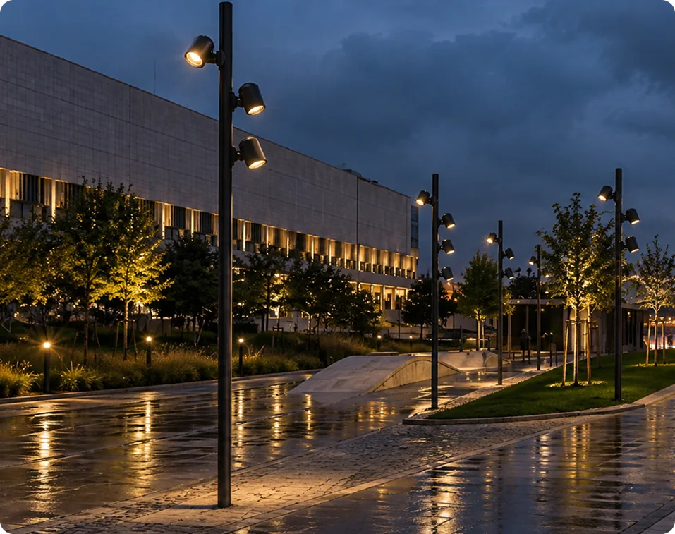 Pole luminaires with multiple spotlight heads along a plaza at night